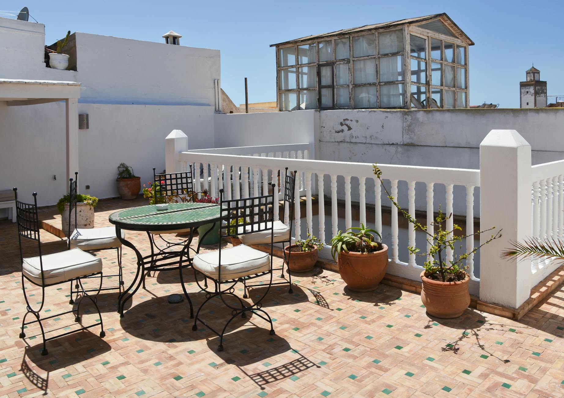 Słoneczny taras na dachu w stylu śródziemnomorskim z roślinami i krzesłami