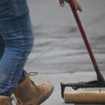 Impregnacja betonu wałkiem na chodniku, widać buty i jeansy