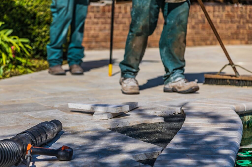 Pracownicy układają płyty tarasowe na zewnętrznym patio w słońcu